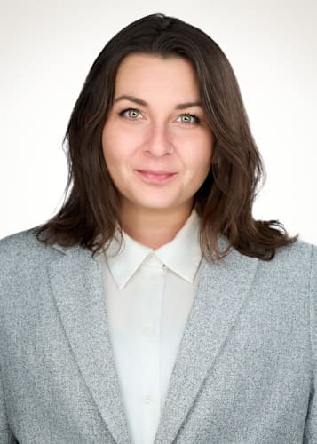 Professional headshot of a woman in a gray blazer and white shirt.