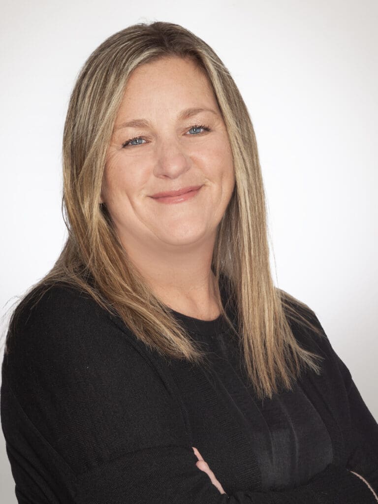 Smiling woman with blonde hair in a black top against white background.